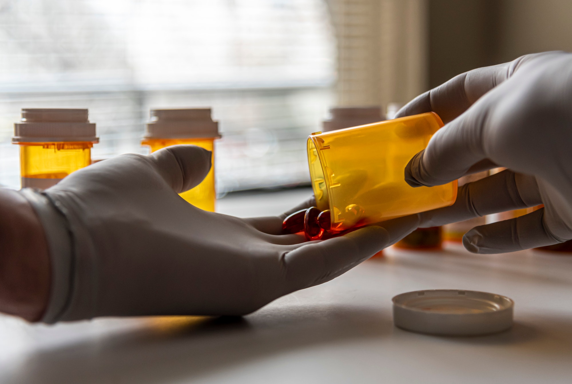 Pouring prescription pills into gloved healthcare providers hands.