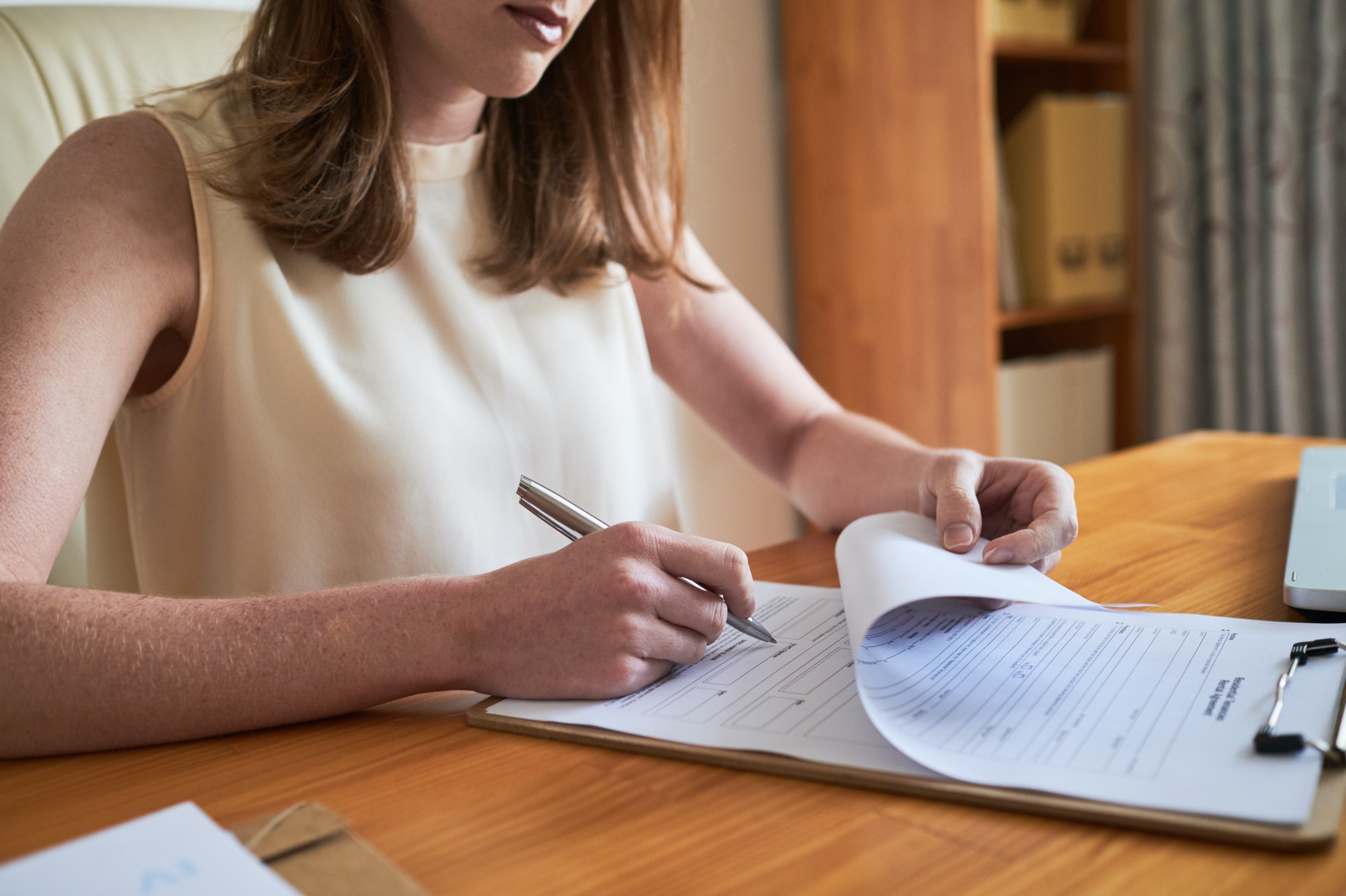 Woman signing paper on clipboard
